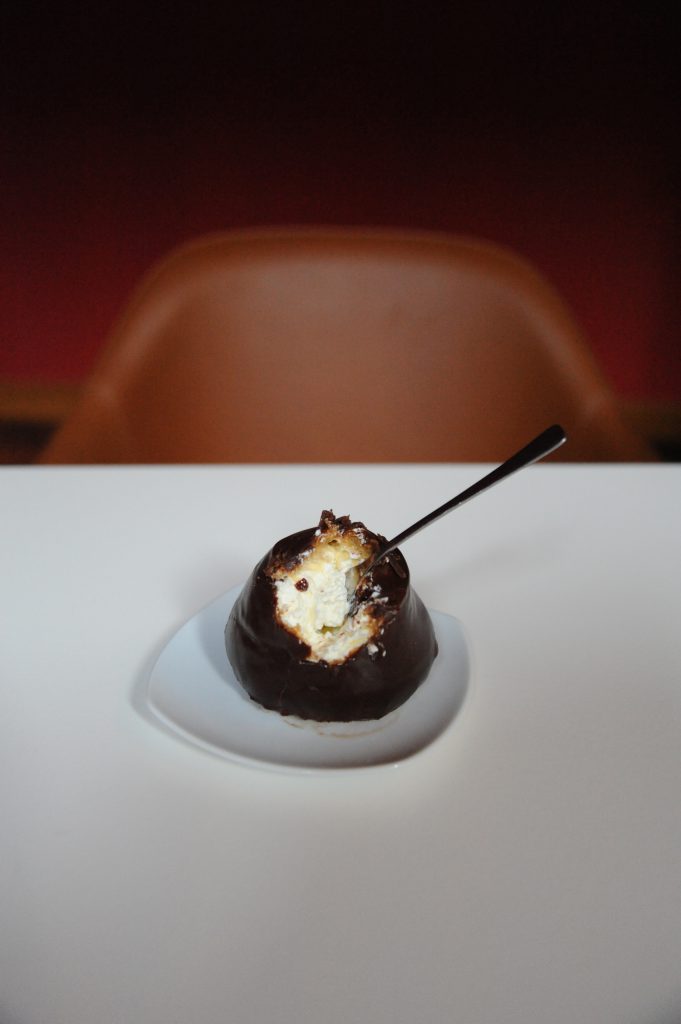 Bossche Bol cake on a white table with a brown chair