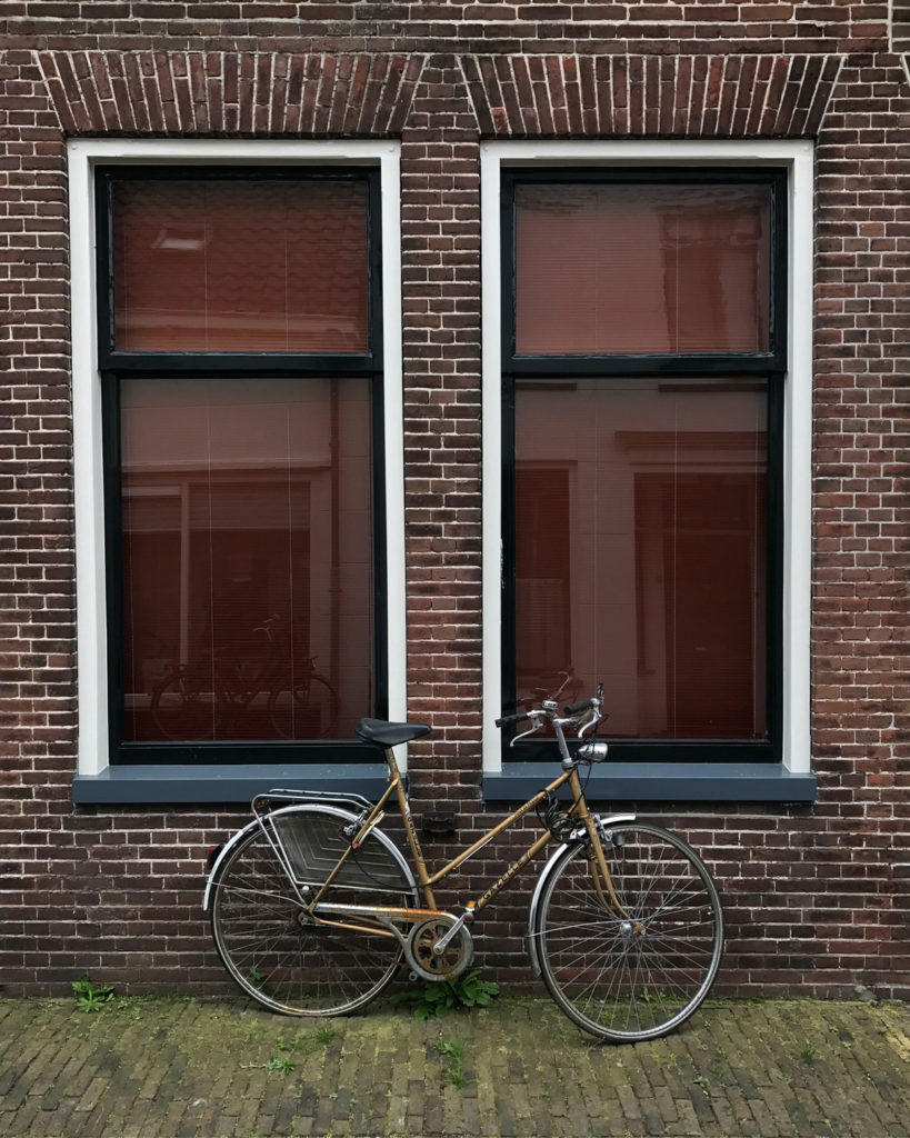 dutch bicycle leant in front of two windows