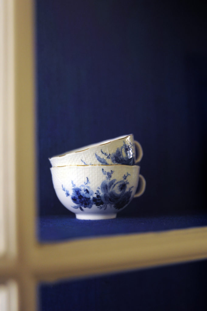 blue and white delft cups in a cupboard with blue background